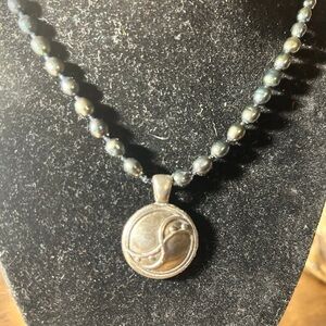 Sterling silver yin yang like symbol pendant with long black beaded chain.